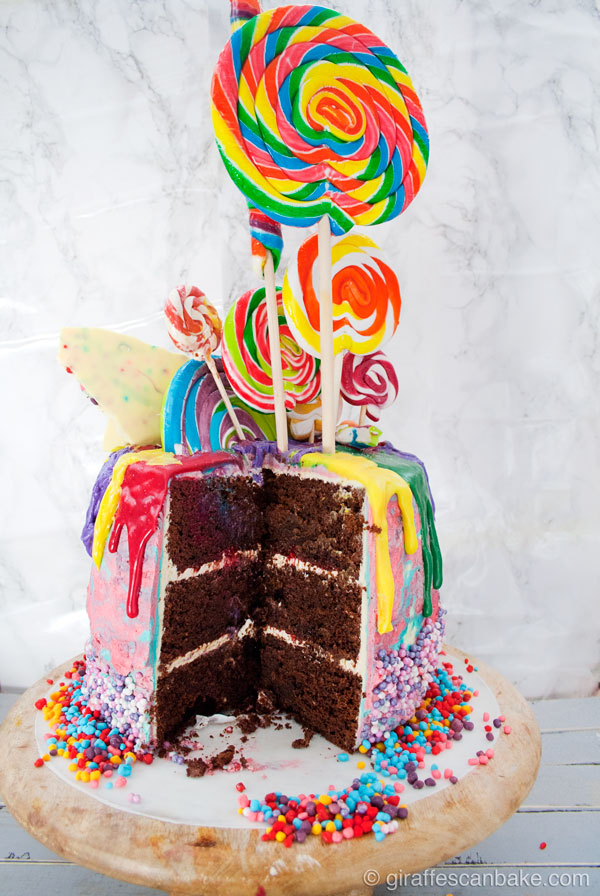Rainbow Lollipop Birthday Cake - Dark Chocolate Mud Cake with Coffee Liquor, filled with boozy Raspberry sauce and Vanilla Swiss Meringue Buttercream. Covered with Pink and Blue Vanilla Swiss Meringue Buttercream and Dripping Rainbow White Chocolate Ganache. Decorated with Rainbow Lollipops! The most fun you can have with a birthday cake!