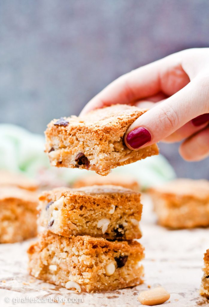 Gluten Free Triple Peanut Blondies - Chewy, moist and packed full of delicious peanut goodness. A peanut butter lover's dream come true! - Taking a blondie from the stack