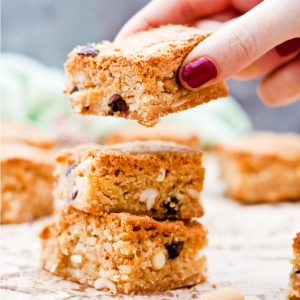 Gluten Free Triple Peanut Blondies - Chewy, moist and packed full of delicious peanut goodness. A peanut butter lover's dream come true! - Taking a blondie from the stack